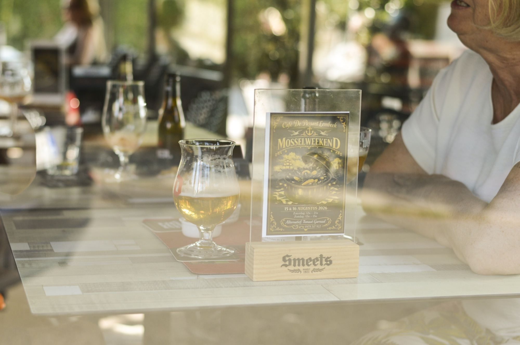 Glas blond bier naast de kaart van het mosselweekend