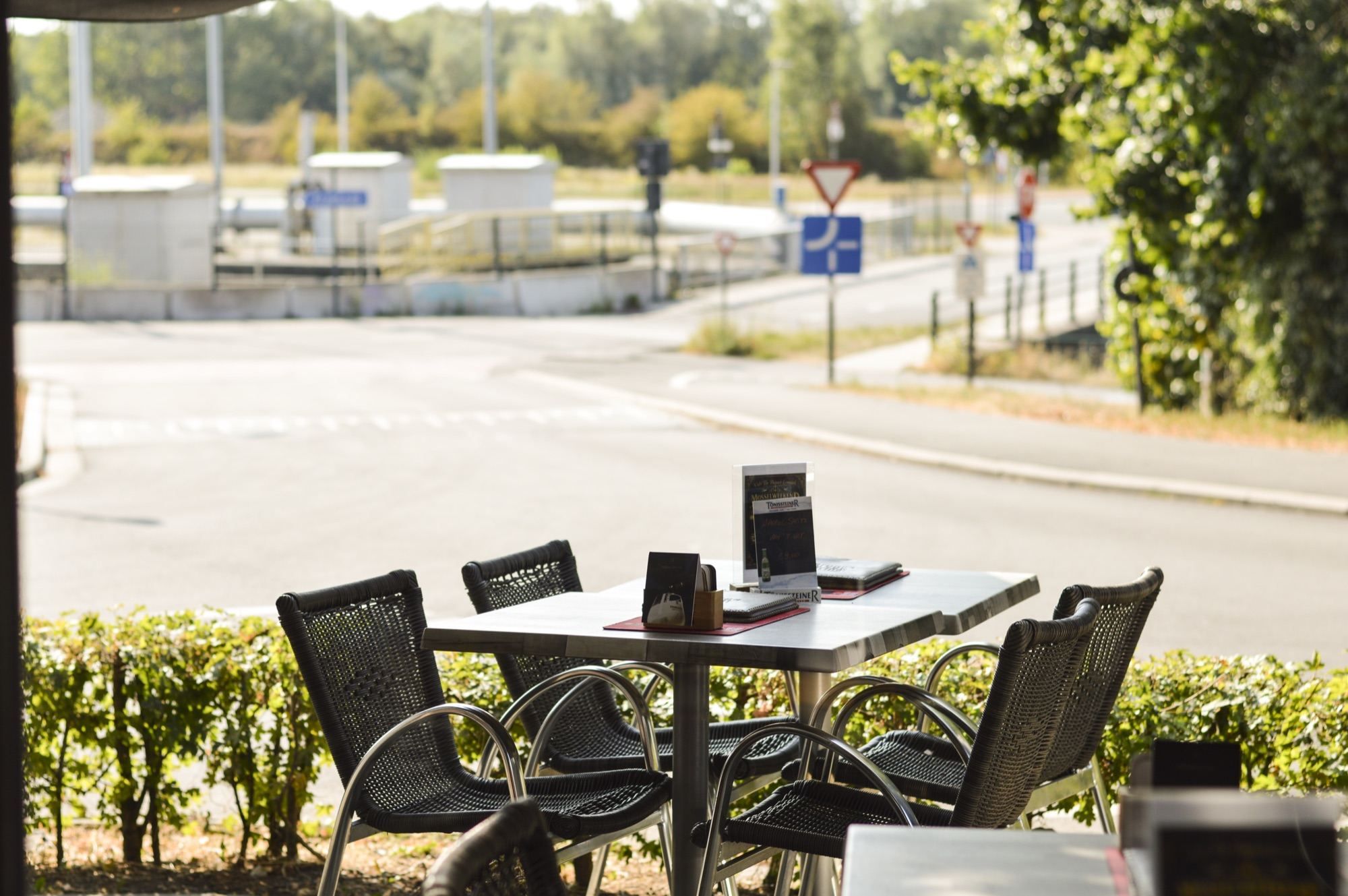 Terrastafel aan de haag met zicht op de weg langs het kanaal