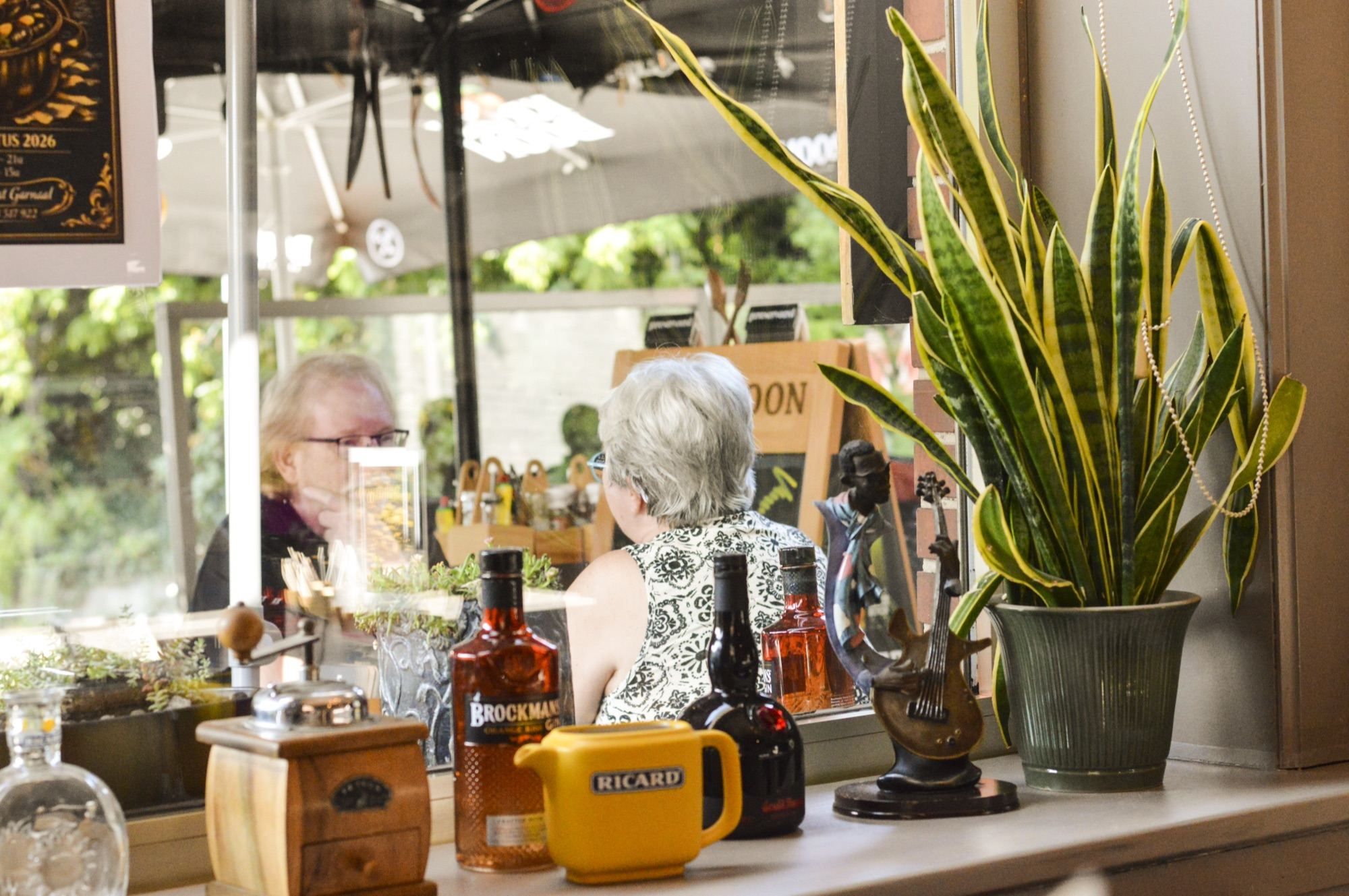 Gasten aan de toog tussen planten en flessen